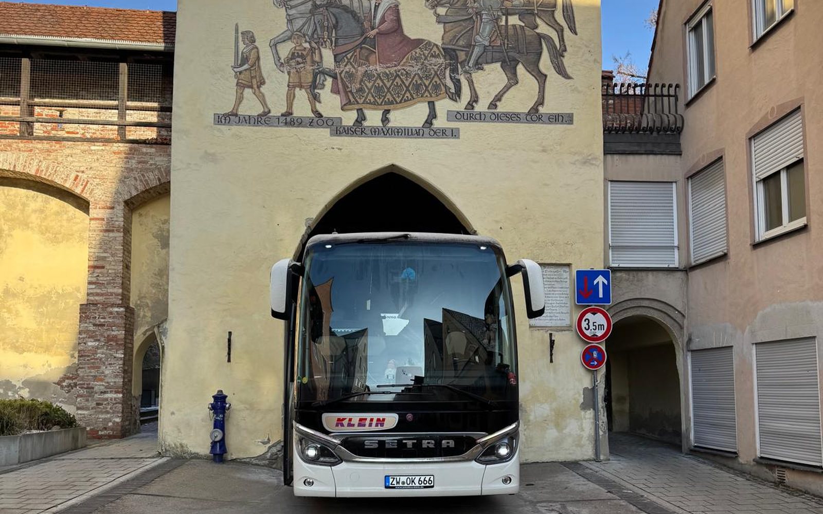 Reisebus von Omnibus Klein unter dem Freskentor eines Südtiroler Stadttors